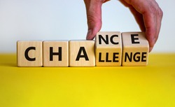 Challenge or chance symbol. Businessman turns cubes and changes the word 'challenge' to 'chance'. Beautiful yellow table, white background, copy space. Business and challenge or chance concept.