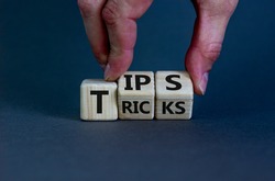 Tips and tricks symbol. Businessman turns cubes and changes the word 'tricks' to 'tips'. Beautiful grey background. Business, tips and tricks concept. Copy space.