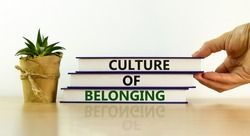 Culture of belonging symbol. Books with words 'culture of belonging' on beautiful white background. Businessman hand. Business, culture of belonging concept. Copy space.