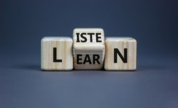 Listen and learn symbol. Turned a wooden cube and changed the word 'listen' to 'learn'. Beautiful grey background, copy space. Business, education and listen and learn concept.