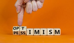 Pessimism or optimism symbol. Businessman turns cubes and changes the word 'pessimism' to 'optimism'. Beautiful orange table, orange background. Business and optimism or pessimism concept. Copy space.