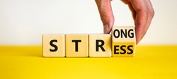 Strong stress symbol. Businessman turns wooden cubes with words 'strong stress'. Beautiful yellow table, white background, copy space. Business and strong stress concept.