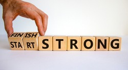 Start and finish strong symbol. Businessman turns wooden cubes, changes words 'start strong' to 'finish strong'. Beautiful white background, copy space. Business and start and finish strong concept.