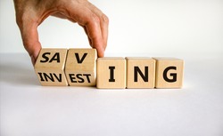 Saving or investing symbol. Businessman turns cubes and changes the word 'investing' to 'saving'. Beautiful white table, white background, copy space. Business and saving or investing concept.