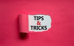 Tips and tricks symbol. Words 'Tips and tricks' appearing behind torn orange paper. Beautiful purple background. Business, Tips and tricks concept. Copy space.