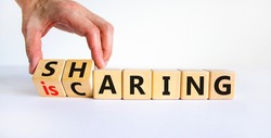 Sharing is caring symbol. Businessman turns wooden cubes with words 'sharing is caring'. Beautiful white table, white background. Business, sharing is caring concept. Copy space.