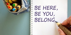 Diversity, belonging symbol. Businessman writing concept words 'Be here, be you, belong' on white note, blue background. Bunch of pencils in bag. Psychological, diversity, belonging concept.