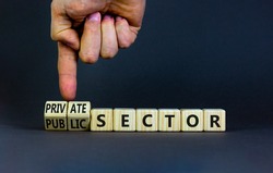 Private or public sector symbol. Businessman turns cubes and changes words 'public sector' to 'private sector'. Beautiful grey background, copy space. Business, private or public sector concept.