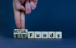 Mutual funds vs ETF symbol. Businessman turns cubes and changes words 'ETF, Exchange-Traded Fund' to 'Mutual funds. Beautiful grey background, copy space. Business and ETF vs mutual funds concept.