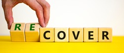 Time to recover symbol. Businessman turns wooden cubes and changes the word 'cover' to 'recover'. Beautiful yellow table, white background. Business, cover or recover concept. Copy space.
