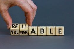 Vulnerable or reliable symbol. Businessman turns wooden cubes and changes the word Vulnerable to Reliable. Beautiful grey background, copy space. Business and vulnerable or reliable concept.