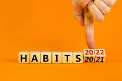 2022 habits and new year symbol. Businessman turns wooden cubes and changes words 'habits 2021' to 'habits 2022'. Beautiful orange background, copy space. Business, 2022 habits and new year concept.