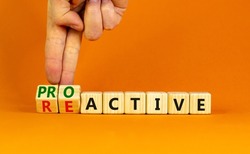Reactive or proactive symbol. Businessman turns wooden cubes and changes the word reactive to proactive. Business and reactive or proactive concept. Beautiful orange background, copy space.