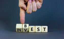 Best invest symbol. Businessman turns wooden cubes and changes the word 'invest' to 'best'. Beautiful grey background. Business and best invest concept. Copy space.
