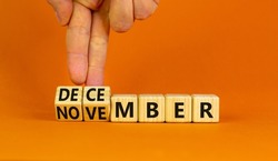 Symbol for the change from November to December, winter. Businessman turns wooden cubes and changes the word 'November' to 'December'. Beautiful orange background, copy space. Happy December concept.