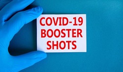 Covid-19 booster shots symbol. Words Covid-19 booster shots on white card. Doctor hand in blue glove. Beautiful blue background. Medical, Covid-19 booster shots concept.