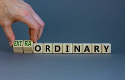 Ordinary or extraordinary symbol. Businessman turnes wooden cubes and changes words 'Ordinary extraordinary'. Beautiful grey background. Business, ordinary or extraordinary concept. Copy space.