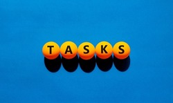 Tasks symbol. The concept word 'tasks' on orange table tennis balls. Beautiful blue table, blue background. Business and task or tasks concept.