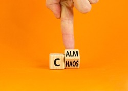 Stop chaos, time to calm. Businessman turns a wooden cube and changes the word 'chaos' to 'calm'. Beautiful orange background, copy space. Business, psuchological and chaos or calm concept.