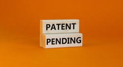 Time to patent pending symbol. Concept words Patent pending on wooden blocks on a beautiful orange background. Business and patent pending concept. Copy space.