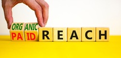 Organic or paid reach symbol. Businessman turns wooden cubes and changes words paid reach to organic reach. Beautiful yellow table white background, copy space. Business organic or paid reach concept.