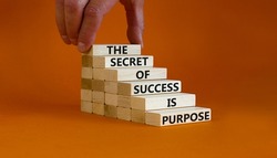 Success and purpose symbol. Wooden blocks with concept words The secret of success is purpose. Beautiful orange background, copy space. Businessman hand. Business, success and purpose concept.