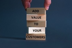 Add value to your customers symbol. Concept words 'Add value to your customers' on wooden blocks on a beautiful grey background, copy space. Businessman hand. Business, customers value concept.