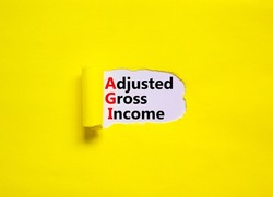 AGI adjusted gross income symbol. Concept words AGI adjusted gross income on white paper. Beautiful yellow background, copy space. Business and AGI adjusted gross income concept.