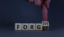 Forgive and forget symbol. Businessman turns a wooden cube and changes the word forgive to forget. Beautiful grey background, copy space. Business, psychological forgive and forget concept.