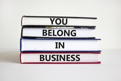 You belong in business symbol. Books with words 'You belong in business' on beautiful white background. Businessman hand. Business and you belong in business concept. Copy space.