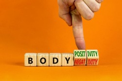 Body positivity or negativity symbol. Psychologist turns cubes, changes words body negativity to body positivity. Orange background, copy space. Psychological, body positive or negative concept.
