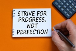 Progress or perfection symbol. Businessman writing words Strive for progress, not perfection on white note. Black calculator. Orange background. Business, progress or perfection concept. Copy space.