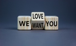 We want and love you symbol. Businessman turns the wooden cube and changes words we want you to we love you. Beautiful grey background, copy space. Business, support we want and love you concept.