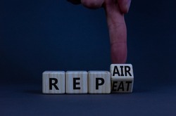 Repeat and repair symbol. Businessman turns a wooden cube and changes the word repeat to repair. Beautiful grey table, grey background, copy space. Business, repeat and repair concept.