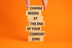 Out from comfort zone symbol. Wooden blocks with words Change begins at the end of your comfort zone. Beautiful orange background, copy space. Businessman hand. Business out from comfort zone concept.