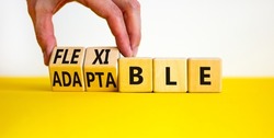 Adaptable or flexible symbol. Businessman turns wooden cubes and changes the word Adaptable to Flexible. Beautiful yellow table white background, copy space. Business, adaptable or flexible concept.