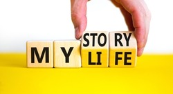 Story of my life symbol. Businessman turns wooden cubes and changes concept words My story to My life. Beautiful yellow table white background. Business story of my life concept. Copy space.