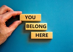 You belong here symbol. Concept words You belong here on beautiful blue table blue background. Businessman hand. Diversity, business, inclusion and belonging concept. You belong here quote.