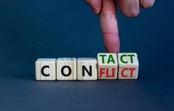 Conflict or contact symbol. Businessman turns wooden cubes and changes the word 'conflict' to 'contact'. Beautiful grey table, grey background, copy space. Business, conflict or contact concept.