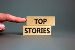 Top stories symbol. Concept words Top stories on wooden blocks on a beautiful grey table grey background. Businessman hand. Business story and top stories concept, copy space.
