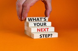 What is your next step symbol. Concept words What is your next step on blocks. Businessman hand. Beautiful orange table orange background. What is your next step business concept. Copy space.