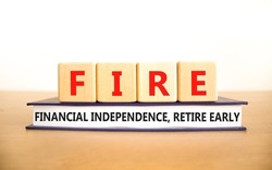FIRE financial independence retire early symbol. Concept words FIRE financial independence retire early on cubes on book. White background. Business FIRE financial independence retire early concept.