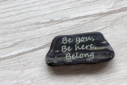 Be here, be you, belong symbol. Beautiful stone with words 'Be here, be you, belong' on beautiful white wooden background. Diversity, business, inclusion and belonging concept.
