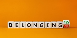 Belonging yes or no symbol. Turned a wooden cube and changed words 'belonging no' to 'belonging yes'. Beautiful orange background. Business and belonging yes or no concept, copy space.