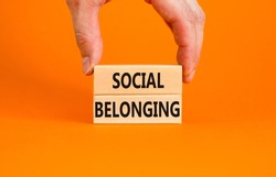 Social belonging symbol. Wooden blocks with concept words Social belonging on beautiful orange background. Businessman hand. Business political social belonging concept. Copy space.