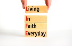 LIFE living in faith everyday symbol. Concept words LIFE living in faith everyday on wooden blocks on white background. Businessman hand. Business LIFE living in faith everyday concept. Copy space.