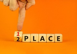 From 2 to 1 place symbol. Businessman turns wooden cubes and changes concept words 2 place to 1 place. Beautiful orange table orange background. Business and from 2 to 1 place concept. Copy space.