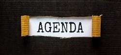 Business and agenda symbol. The concept word 'agenda' appearing behind torn black paper. Beautiful black background, copy space. Business and agenda concept.