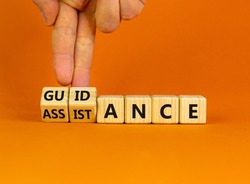 Guidance and assistance symbol. Businessman turns cubes, changes words 'assistance' to 'guidance'. Beautiful orange background, copy space. Business, guidance and assistance concept.