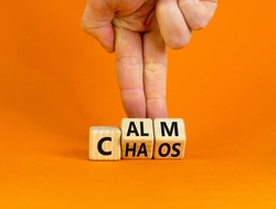 Stop chaos, time to calm. The words 'chaos' and 'calm' on wooden cubes. Beautiful orange background, copy space. Businessman hand. Business and chaos or calm concept.